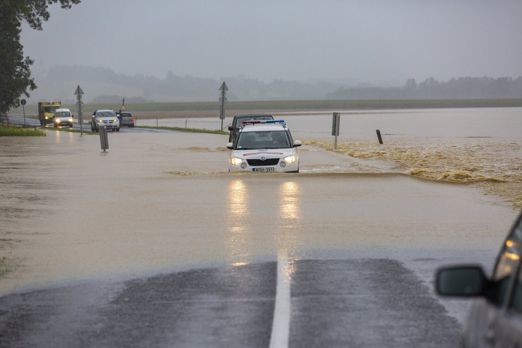 A katasztrófavédelm gépjárműve és egy terepjáró halad a nagy esőzés miatt vízzel elárasztott Csurgót és Gyékényest összekötő úton, a Somogy megyei Porrogszentkirály közelében 2020. július 25-én. A másik fotón autók állnak ugyanott. MTI/Varga György (2 / 2. kép)